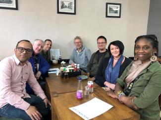 Adults sitting around a cafe table looking at the camera and smiling