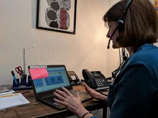 A woman sitting in front of a laptop computer and wearing a headset