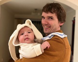 A man holding a baby, both looking at the camera