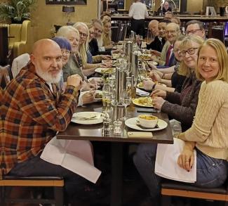 A group of people sitting around a restaurant table, looking at the camera and smiling