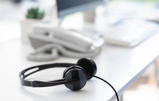 A pair of headphones on a desk, with a telephone behind it