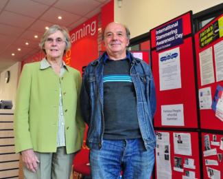 A man and woman standing next to information boards, smiling for the camera