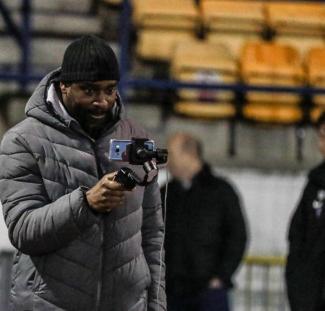 A man filming on his smartphone in a football stadium