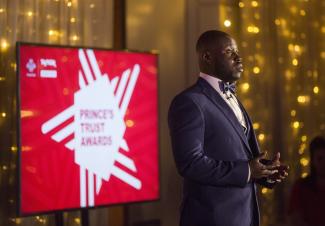 A man in a tuxedo doing a public speaking event