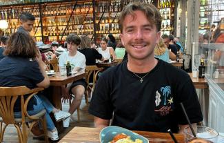 A man in a restaurant sitting at a table and smiling