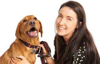 A woman smiling, next to her pet dog