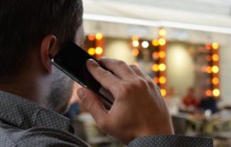 The back of a man's head as he speaks into a mobile phone. 