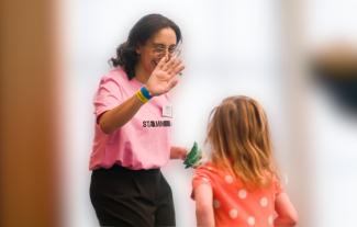 A woman high fiving a young girl, who's back is to the camera