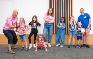 A man next to a group of children, all smiling and posing for the camera