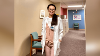 A woman in a medical outfit, standing and smiling