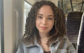 A young woman sitting on a train, smiling for the camera