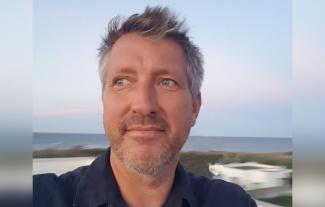 A man on a beach looking to the left and smiling