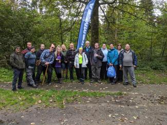 A group of people in an outdoor setting standing beside a banner