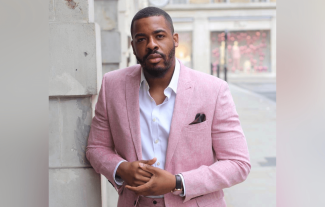 A smartly dressed man leaning against a wall