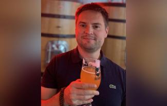 A man holding up a glass of beer and smiling for the camera