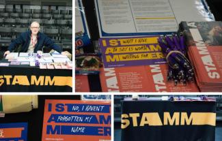 A man standing at an information desk, with postcards, pens and leaflets next to him