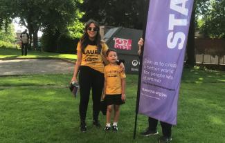 A woman and son in running clothes standing by a banner