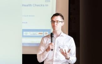 A man speaking into a microphone and gesturing with his hand