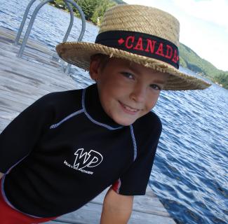 A young boy wearing a straw hat sitting on a jetty