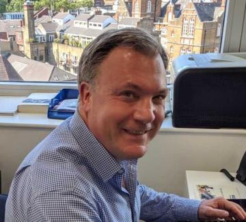 A man at a desk, smiling