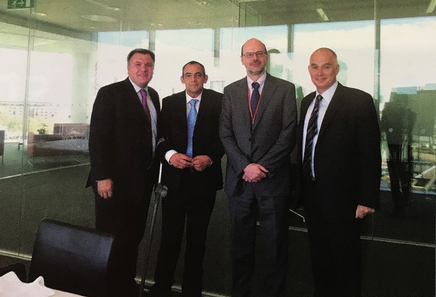 Four men in suits standing and looking at the camera