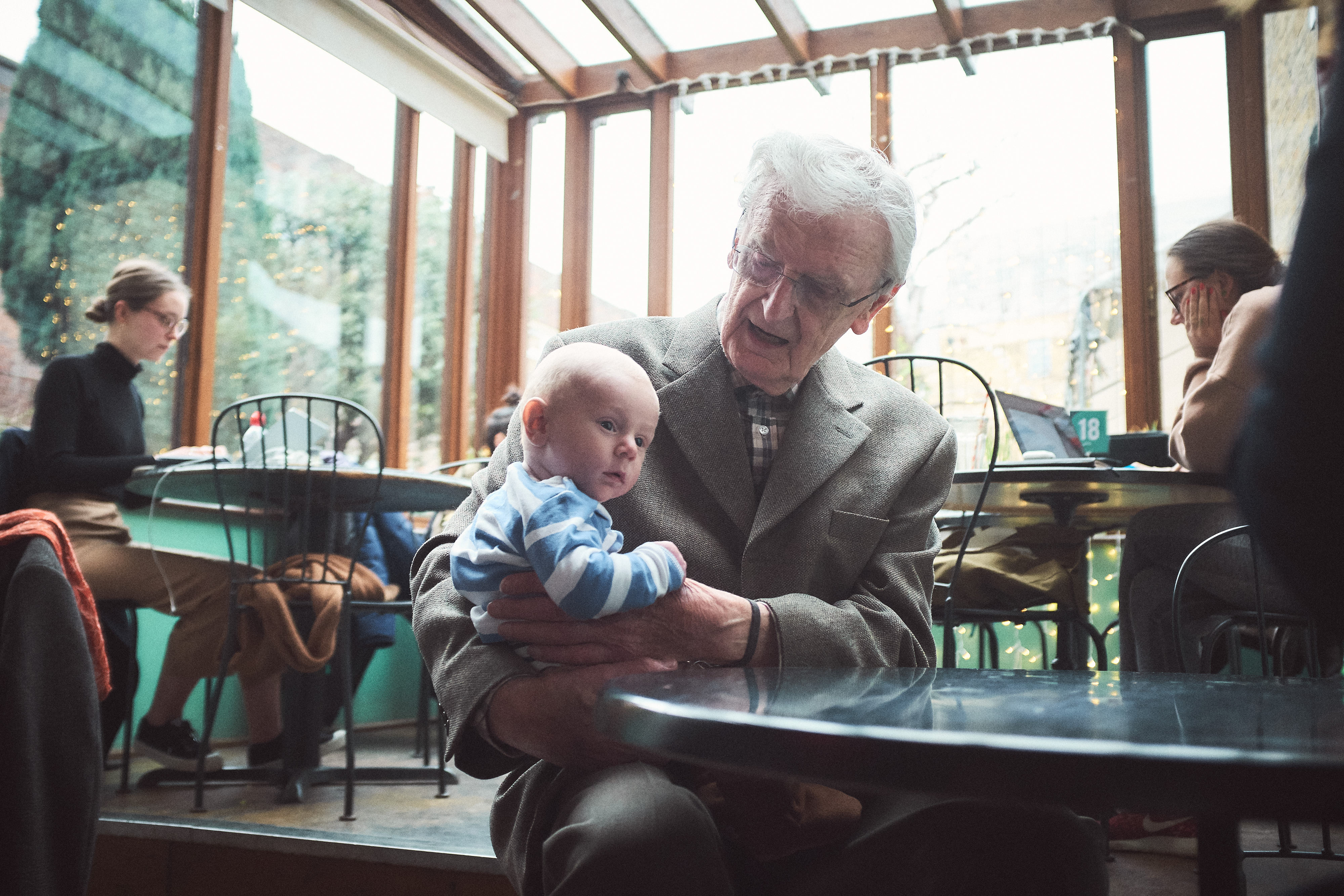 An elderly man sitting with a baby on his knee