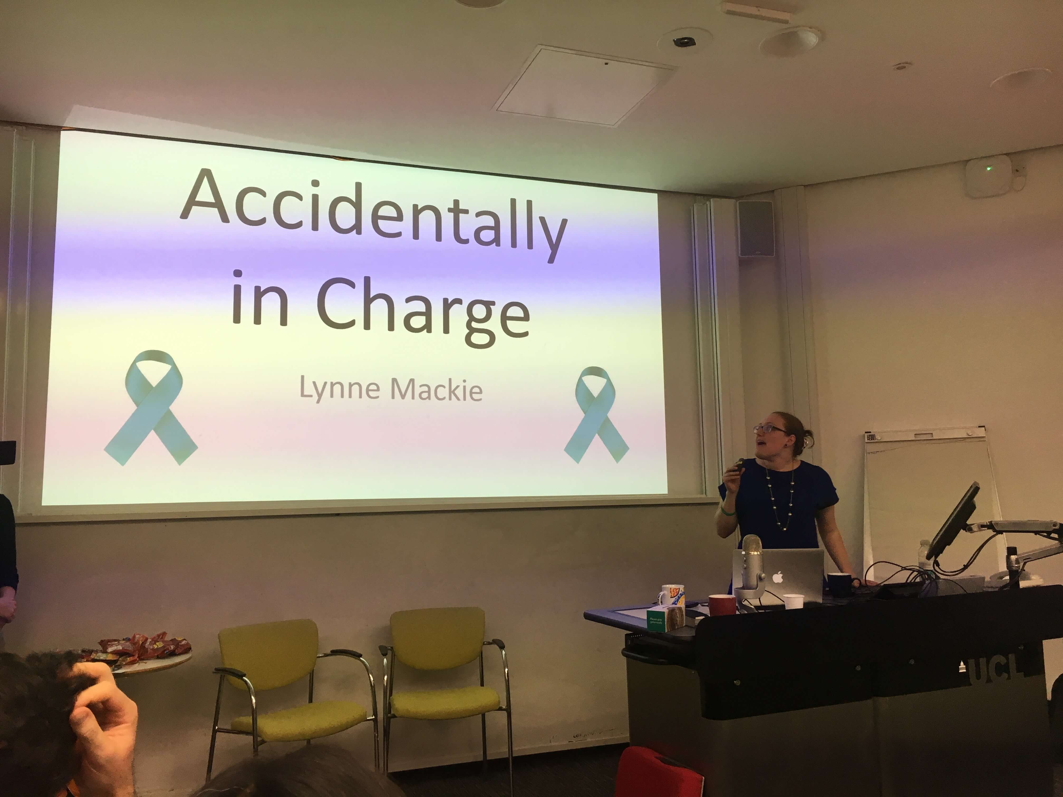 A woman speaking in front of a powerpoint presentation