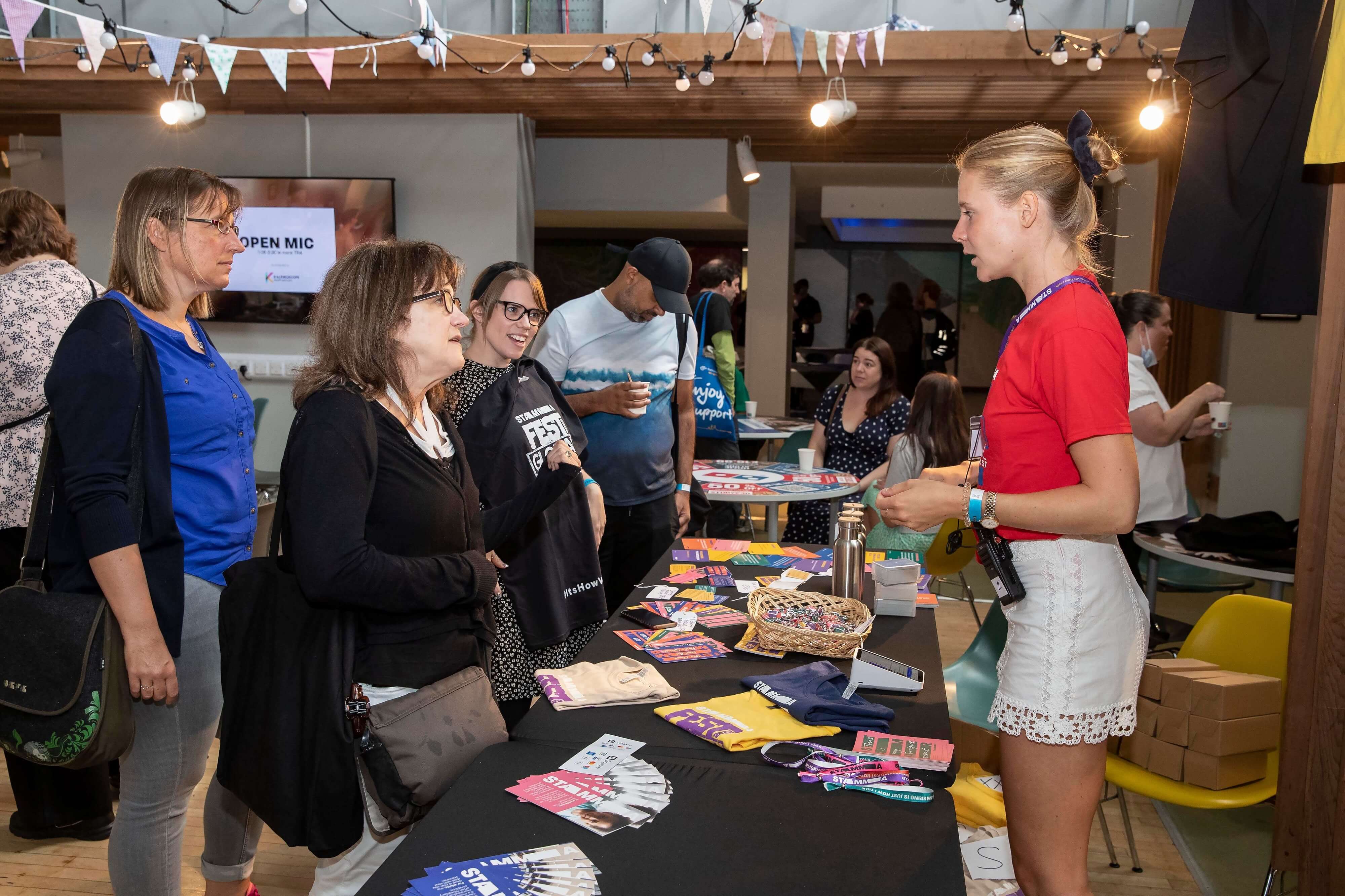 A woman standing beside a table talking to people on the other side of it