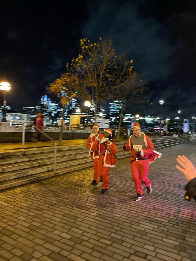 Three people running dressed as Father Christmas